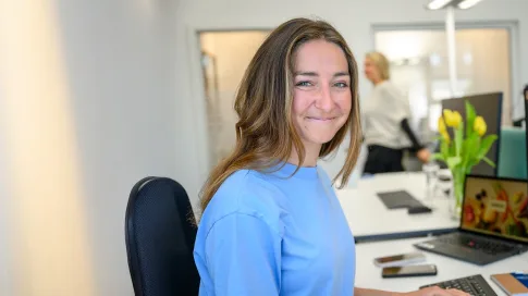 Eine lächelnde Frau sitzt in einem Büro.