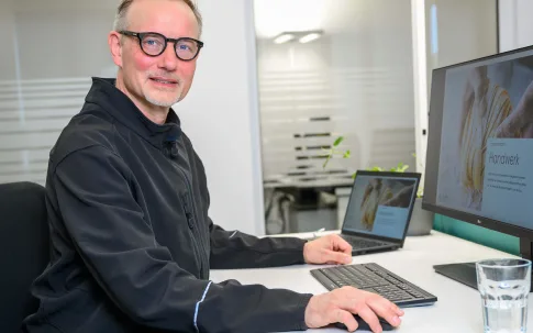 Ein Mitarbeiter sitzt an einem Schreibtisch in einem Büro.